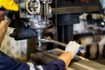 Professional caucasian white ethnicity male technician operating the heavy duty machine in the lathing factory. Technician in safety and helmet suit controlling a machine in factory.
