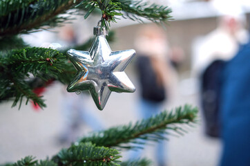 Nahaufnahme eines silbernen Sternes an einem Zweig einer weihnachtlich geschmückten Nordmanntanne...