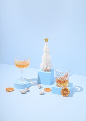  Christmas table with drinks, oranges and Christmas tree against a blue background. New Year's Eve...