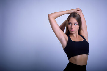 Fototapeta na wymiar Attractive woman posing in black lingerie in studio. Slender caucasian young girl with perfect body posing with raised arms, showing her perfect curves.