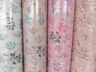Colorful material fabric rolls texture samples. Fabric rolls of colorful flowers material. Carton reels with colorful textile on a retail market stall.