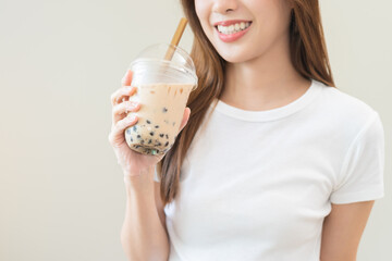Beverage and food concept, Happy asian young woman hand holding plastic cup, glass of drink bubble, pearl milk tea with straw, cute girl drinking ice cold tea with tapioca boba ball popular in Taiwan. - Powered by Adobe