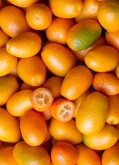 Top view of bunch of fresh kumquats in the organic food market. Some kumquats is cutted.