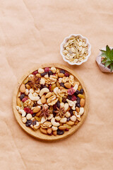 Wooden bowl with mixed nuts on a natural background from above. Healthy food and snacks. Walnut, almonds, hazelnuts and cashews. Raisins and cranberries