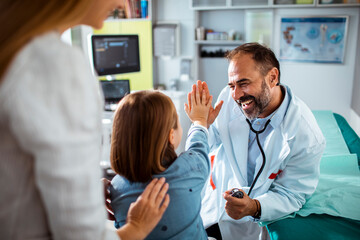Smiling doctor high fiving little girl at the hospital