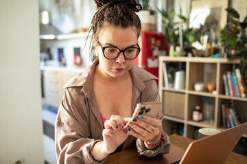 Young woman with glasses using smartphone at home