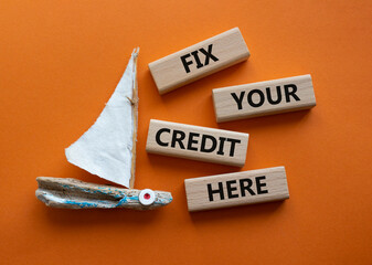 Fix your credit here symbol. Concept words Fix your credit here on wooden blocks. Beautiful orange background with boat. Business and Fix your credit here concept. Copy space.