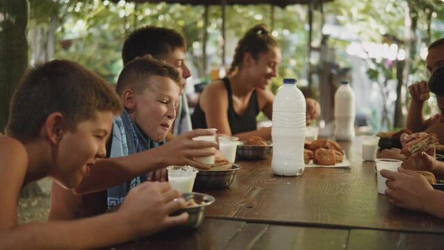 Teenagers in the camp have breakfast together at the table