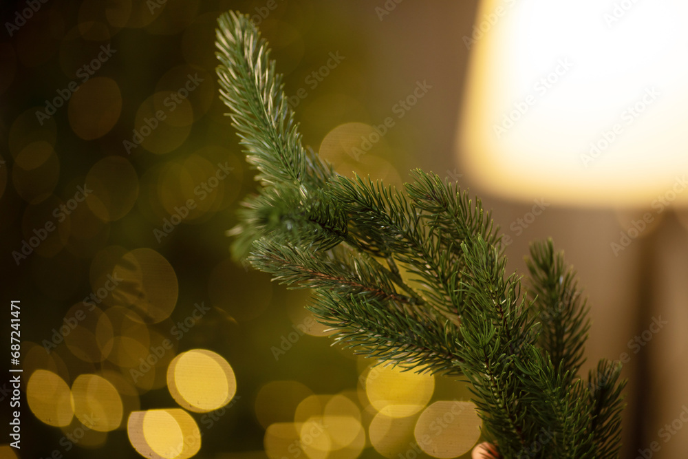 Poster artificial spruce branch with lights with bokeh effect. beautiful christmas tree against blurred lig