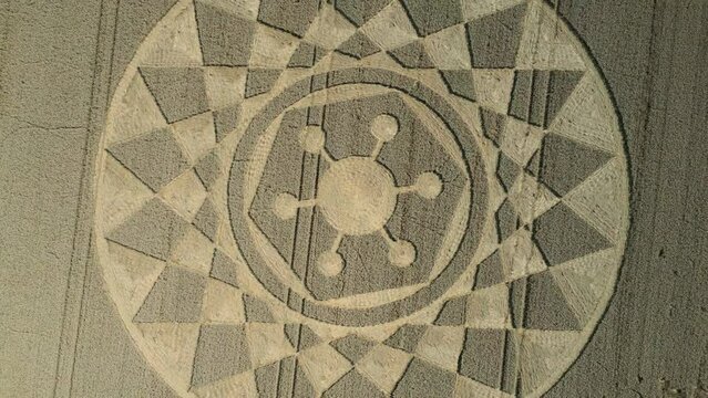 Aerial rise reveal clip of an intricate geometric crop circle formation in a wheat field in Wiltshire, England, UK 