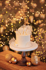 White Christmas sweets cake with 2024 symbol on wooden background with gold pine tree with bokeh...