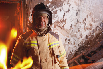 Obraz premium Portrait brave and strong Firefighter in burning building, house burn with open flames. Concept dangerous work of rescue services