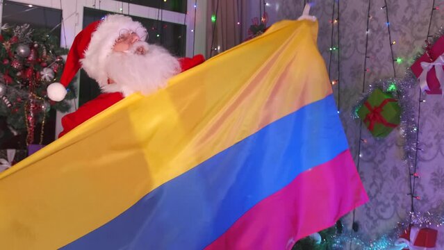 Colombia support. Santa waving Colombian flag at Christmas party next to Christmas tree, garlands, gifts and fir wreaths. Soccer match.