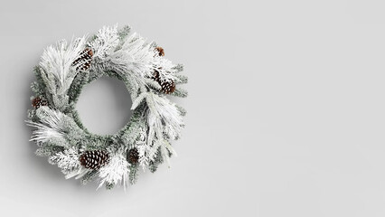Cristmas wreath with flocked greenery and pinecones on copy-space background. © Carterson