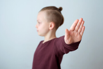 Focus on palm child saying stop or not accepting abuse, bullying on a gray background. Violence...