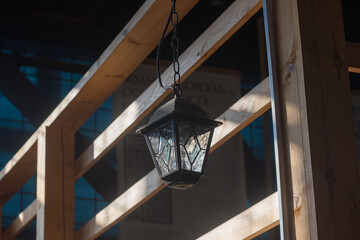 electric lantern stylized as an old street lamp hangs on a wooden beam near the railing of the stairs. natural light.