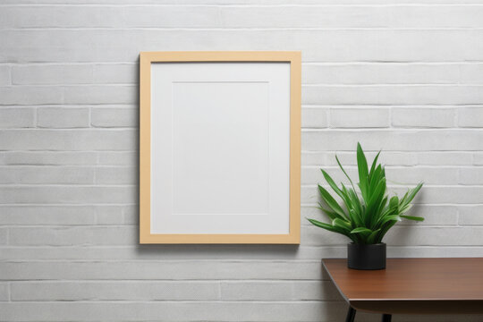 A picture frame hangs on a brick wall, complemented by a potted plant. Perfect for home decor or interior design projects
