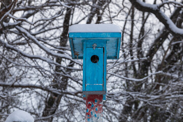 small blue birdhouse with snow on it