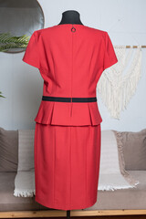 Elegant red dress with short sleeves and a black belt. Rear view of a tailor's mannequin. Demonstration of women's clothing.