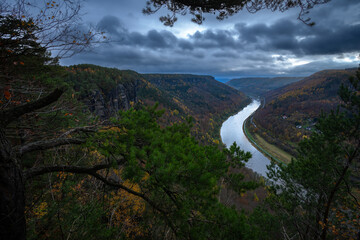 Great view to the amazingly deep valleys and dark forests with stormy clouds overhead in the...