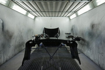 The photograph captures the scene of an automotive workshop, showcasing the process of painting...