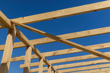 the wooden frame of the building against the blue sky