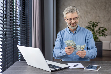 Successful mature banker financier investor at workplace counting money dollars cash, senior...