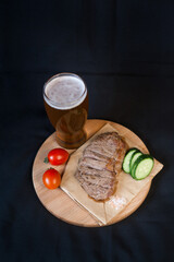 Fried meat with green vegetables with a glass of beer