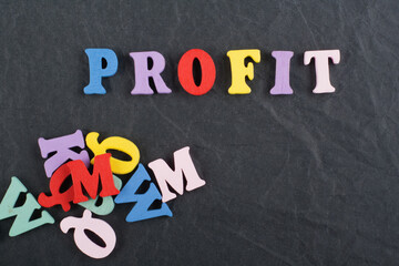 PROFIT word on black board background composed from colorful abc alphabet block wooden letters, copy space for ad text. Learning english concept.