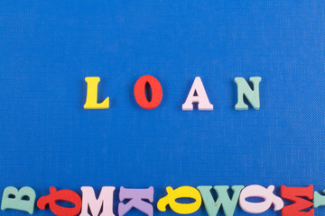 LOAN word on blue background composed from colorful abc alphabet block wooden letters, copy space for ad text. Learning english concept.