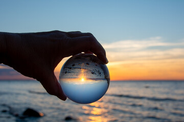 Beach and sea reflected in a ball in a human hand - obrazy, fototapety, plakaty