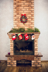 Home decorative fireplace made of bricks with candles, decorated with New Year's details, socks...