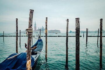 A serene lake landscape is interrupted by the wooden gondola tied to the pier, creating a sense of...