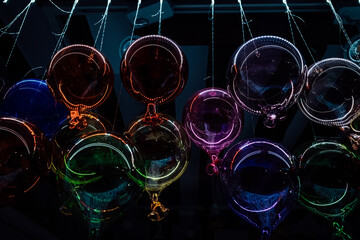 Colorful orbs suspended by delicate strings, floating in a sea of light, encircling a glass sky