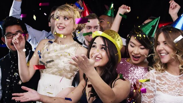 Friends party, confetti and dancing with energy, birthday celebration and new year with music, crazy and happy smile. Men and women celebrate social event with diversity in black studio background