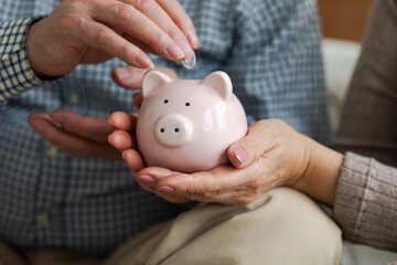 Saving money investment for future. Senior adult mature couple hands putting money coin in piggy...