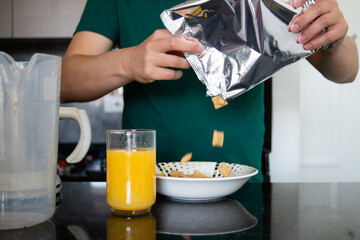 a man preparing a healthy breakfast with orange juice and cereal