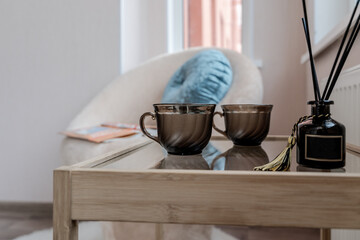 black mugs on a wooden table. an armchair and a pillow