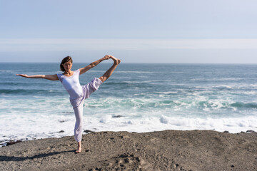 A girl does yoga on the ocean