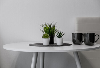 a white kitchen table. round table with mugs and flowers in the kitchen