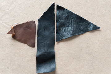 grungy cut brown and black leather pieces on plain brown paper