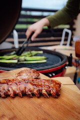 A smoky aroma fills the air as a person skillfully prepares a succulent dish of barbecued ribs on a wooden cutting board, surrounded by the warmth of indoor grilling and the comfort of a family-style
