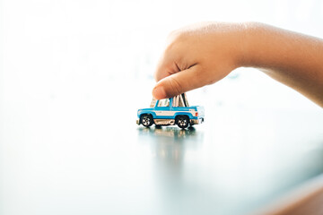 The grasp of a child's hand on a toy car represents the limitless imagination and untamed curiosity of youth, as they dream of the endless possibilities that await them in the world of vehicles - obrazy, fototapety, plakaty