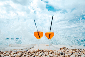 Two glasses of tangy orange liquid, adorned with straws and perched on rocks, invite you to bask in the breathtaking landscape of a snowy mountain, with the sky and clouds as your witness, while savo