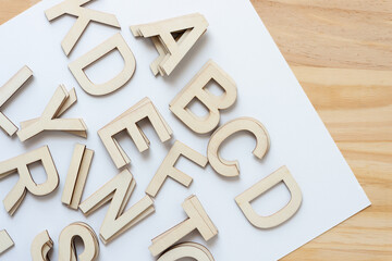 wooden alphabet letters on white paper and wood