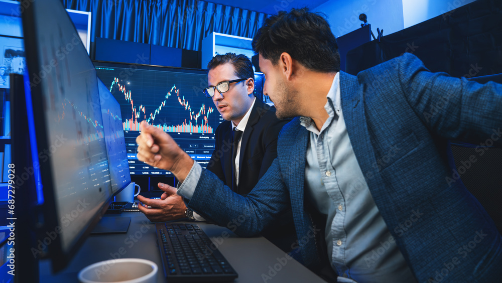Poster two stock exchange traders discussing dynamic investment graph in currency rate on monitor at night.