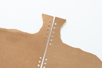 torn brown cardboard with round binding holes on white