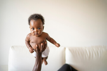 African American baby held in the air by his father in his arms