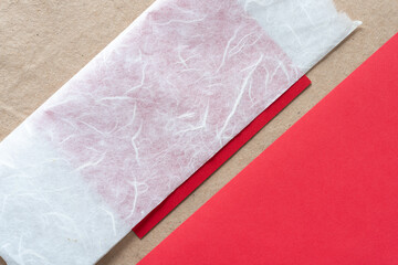 tissue and solid red paper pieces on plain brown paper