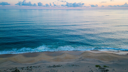aerial blue ocean water sandy tropical beach at sunset 